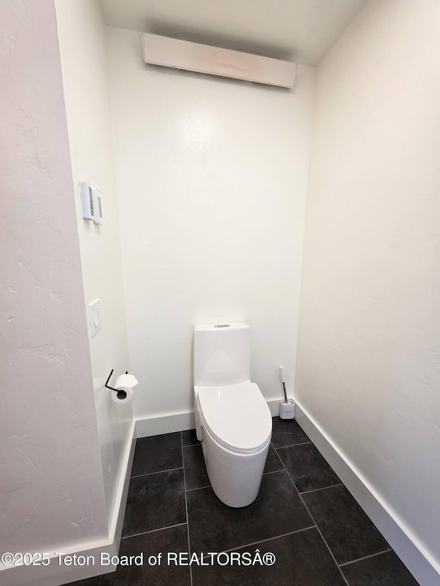 bathroom with tile patterned floors, toilet, baseboards, and an AC wall unit