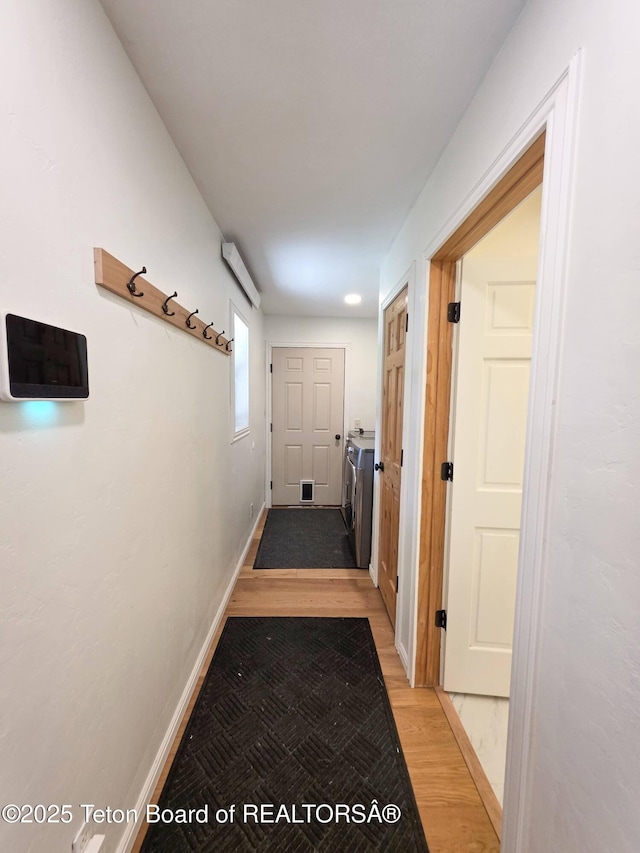 hall with baseboards, light wood finished floors, and visible vents