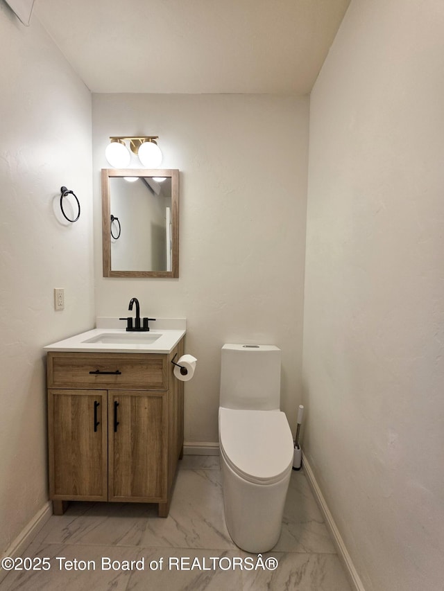 half bath featuring vanity, baseboards, and marble finish floor