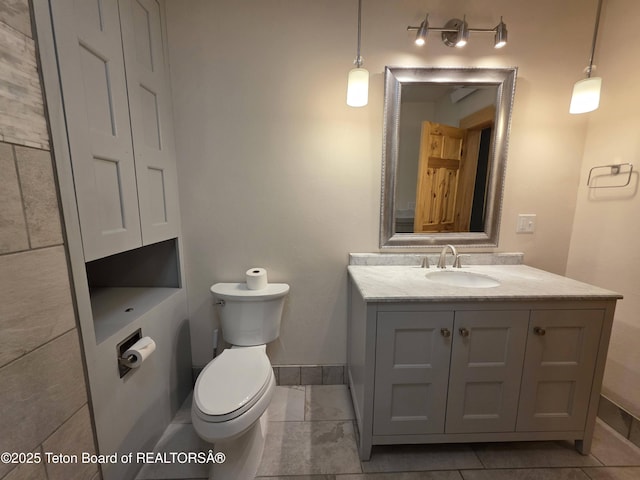 bathroom featuring toilet, baseboards, and vanity