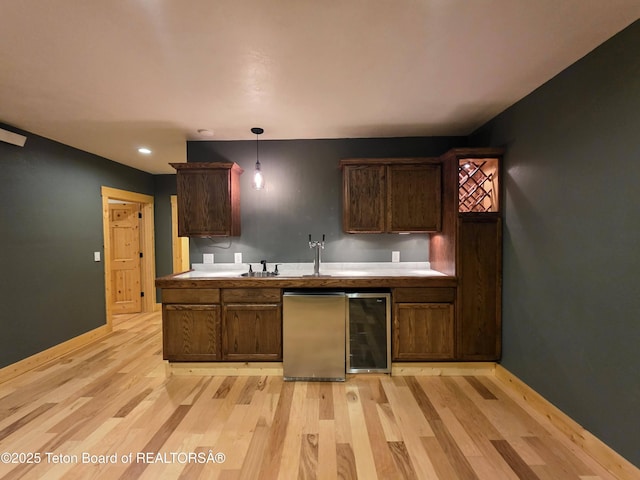 kitchen with baseboards, light wood-style floors, light countertops, and hanging light fixtures