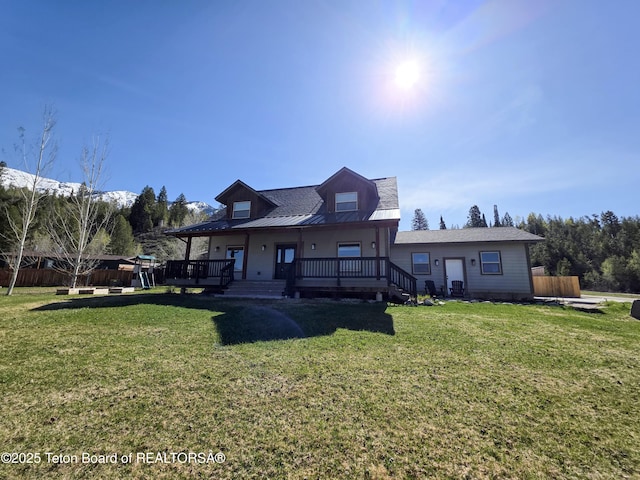 rear view of house featuring a yard, fence, and metal roof