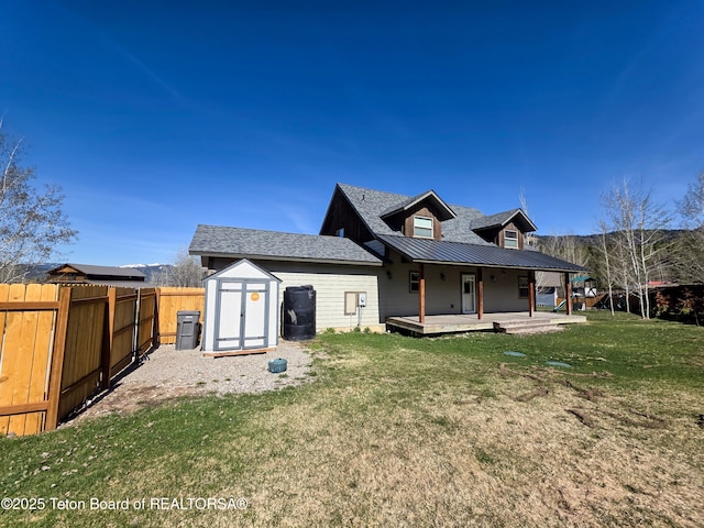 back of property featuring a lawn, an outbuilding, fence, metal roof, and a storage shed