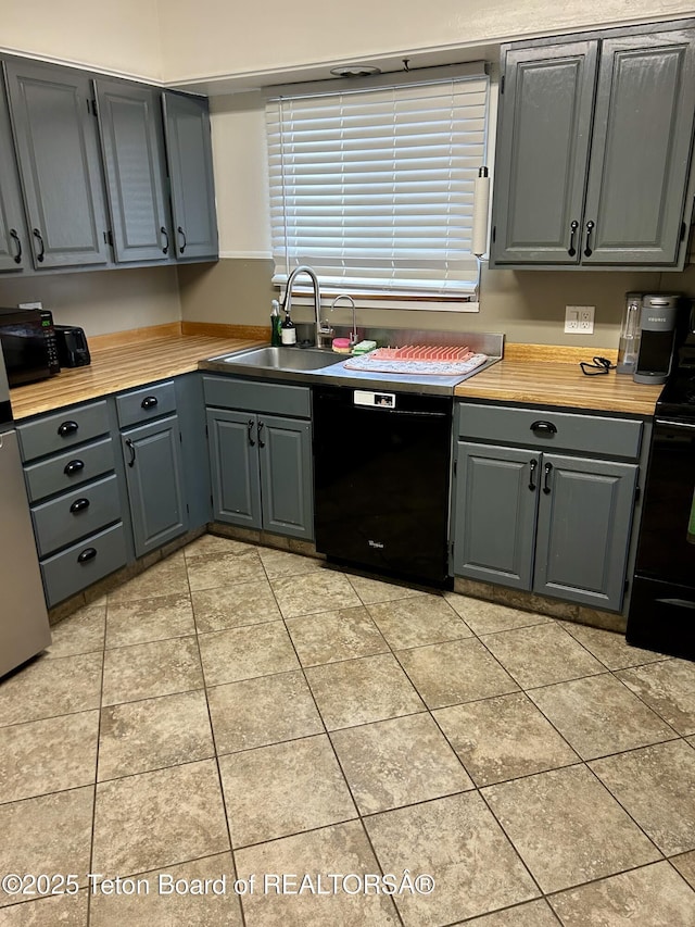 kitchen with black appliances, gray cabinets, a sink, light tile patterned flooring, and light countertops