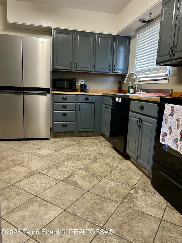 kitchen with black appliances, light tile patterned floors, gray cabinetry, and a sink