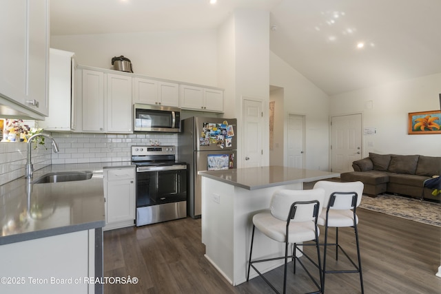 650 Centennial Mountain St, Driggs, ID 83422 - kitchen with appliances with stainless steel finishes, a sink, white cabinets, a kitchen bar, and high vaulted ceiling
