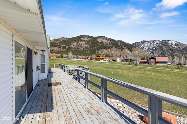 wooden deck with a mountain view and a lawn