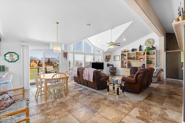 living area featuring a chandelier, stone tile floors, vaulted ceiling, and a ceiling fan