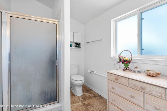 full bath with vaulted ceiling, a stall shower, toilet, baseboards, and stone finish floors