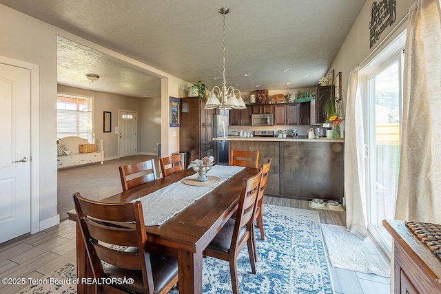 350 Little Greys Loop, Etna, WY 83118 - dining area featuring a chandelier, a textured ceiling, light wood-type flooring, and baseboards