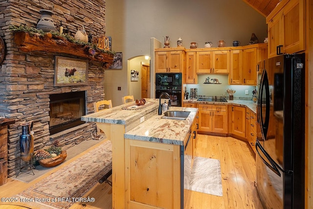 109 Redwood Rd, Star Valley Ranch, WY 83127 - kitchen with black appliances, a sink, high vaulted ceiling, light wood-type flooring, and arched walkways