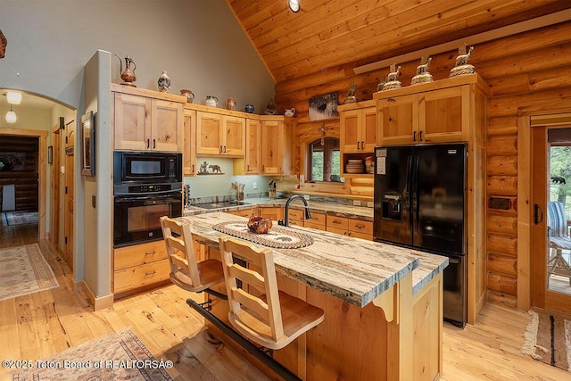 109 Redwood Rd, Star Valley Ranch, WY 83127 - kitchen featuring black appliances, arched walkways, rustic walls, a sink, and light countertops