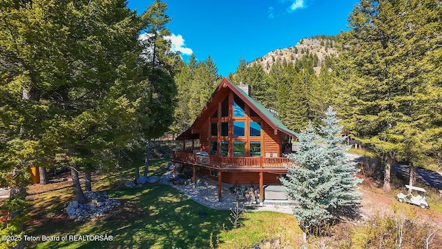 109 Redwood Rd, Star Valley Ranch, WY 83127 - back of property featuring log veneer siding, a wooden deck, a view of trees, and a yard