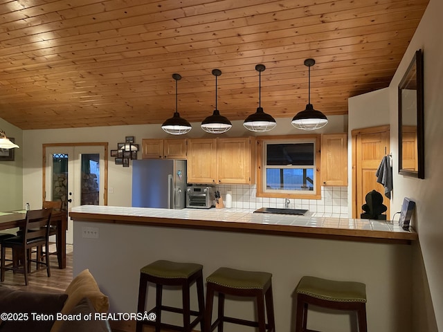 51 Cheyenne Cir, Star Valley Ranch, WY 83127 - kitchen with high end refrigerator, tile countertops, decorative backsplash, a kitchen breakfast bar, and wooden ceiling