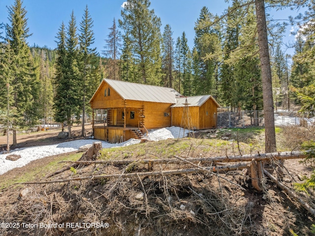 2 Porcupine Cir, Dubois, WY 82513 - view of side of home featuring log exterior, covered porch, a metal roof, and a forest view