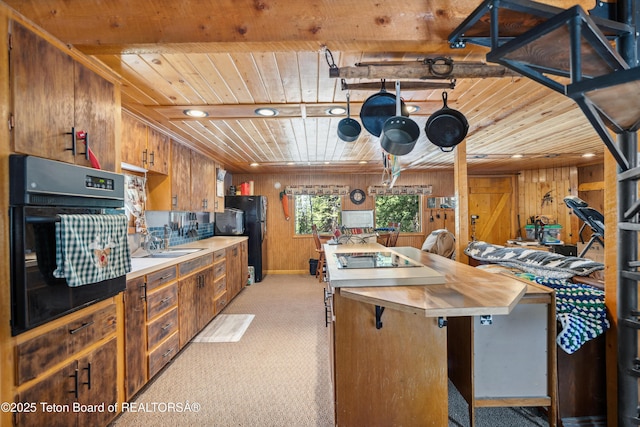 2 Porcupine Cir, Dubois, WY 82513 - kitchen with black appliances, wooden ceiling, wood walls, light carpet, and brown cabinets