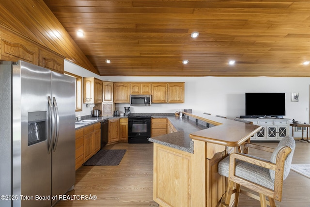 51 Buckaroo Cir, Etna, WY 83118 - kitchen with black appliances, a peninsula, dark countertops, wood finished floors, and wood ceiling