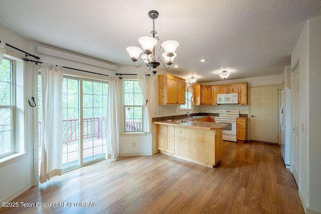 99 Sugar Lf, Star Valley Ranch, WY 83127 - kitchen with white appliances, a peninsula, wood finished floors, a sink, and a chandelier