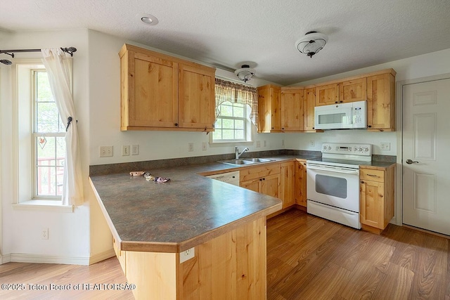 99 Sugar Lf, Star Valley Ranch, WY 83127 - kitchen featuring white appliances, a sink, dark countertops, a peninsula, and light wood-style floors
