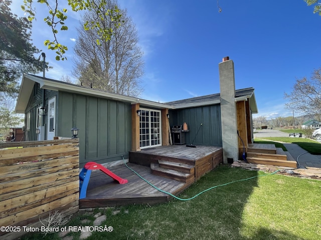 325 1st St N, Cokeville, WY 83114 - back of house with board and batten siding, a chimney, a wooden deck, and a lawn
