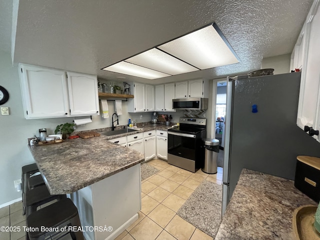 325 1st St N, Cokeville, WY 83114 - kitchen featuring stainless steel appliances, a sink, a peninsula, white cabinetry, and light tile patterned floors