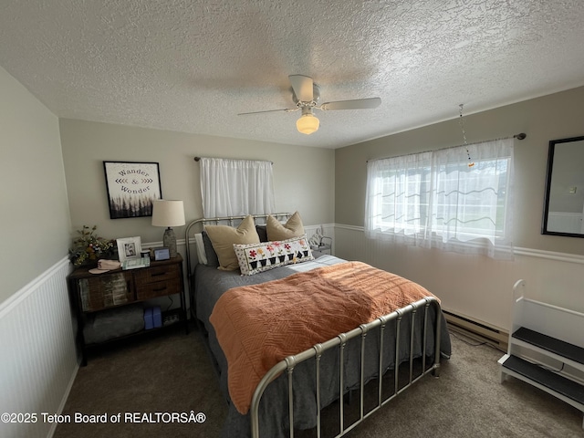 325 1st St N, Cokeville, WY 83114 - bedroom with baseboard heating, wainscoting, carpet flooring, a textured ceiling, and ceiling fan