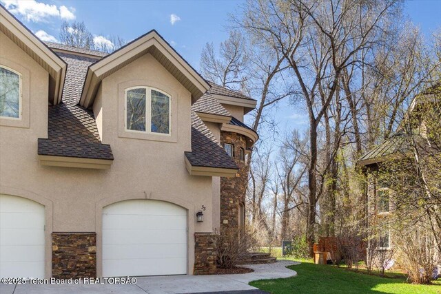 33 Willowbrook Dr, Driggs, ID 83422 - view of side of property with stucco siding, stone siding, an attached garage, and roof with shingles