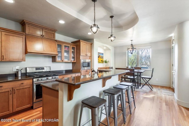 33 Willowbrook Dr, Driggs, ID 83422 - kitchen featuring stainless steel appliances, brown cabinetry, a breakfast bar, a kitchen island with sink, and light wood-type flooring