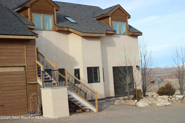 60 Flying Frog St, Dubois, WY 82513 - back of property with stairway, a shingled roof, and stucco siding