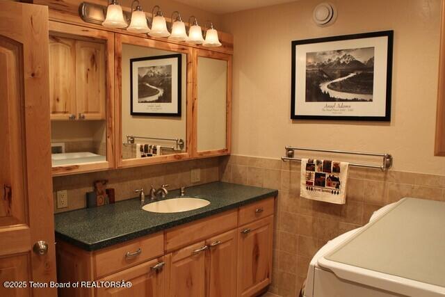 bathroom featuring washer / clothes dryer, tile walls, and vanity