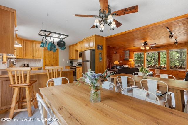 dining area featuring ceiling fan and wood walls