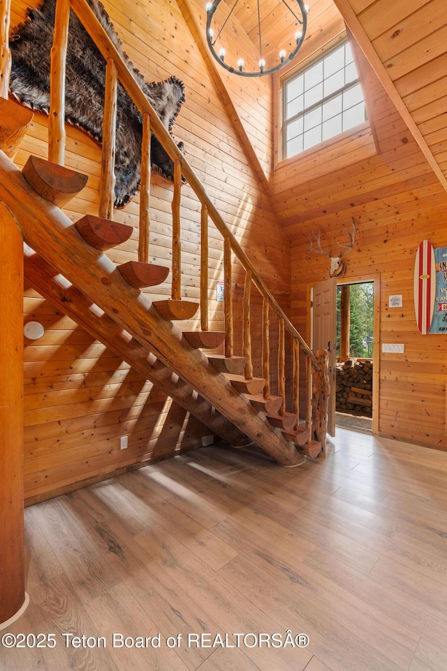 stairs featuring a towering ceiling, wooden walls, wood finished floors, and wooden ceiling