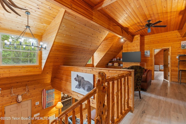 corridor featuring an upstairs landing, wooden ceiling, wooden walls, wood finished floors, and a chandelier