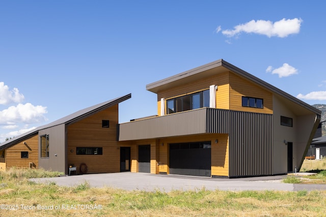 view of front of house with an attached garage, a balcony, and driveway
