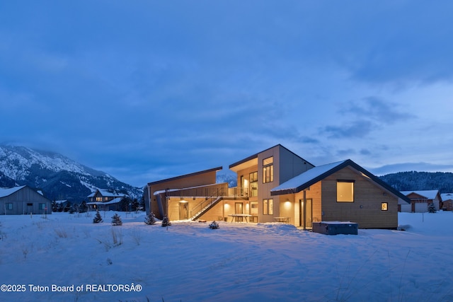 snow covered house featuring a mountain view and stairs