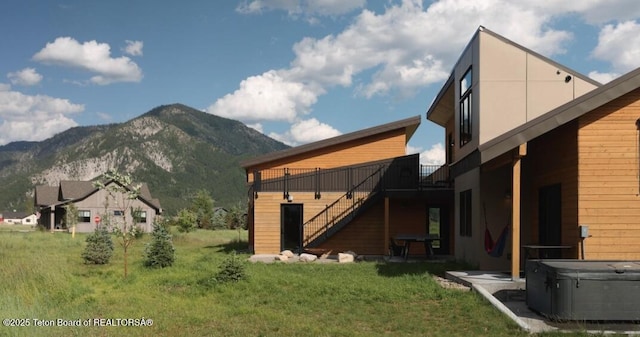 back of property with stairway, a deck with mountain view, and a hot tub
