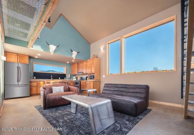 living room featuring concrete floors, high vaulted ceiling, and baseboards