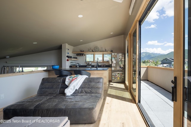 living area featuring vaulted ceiling, a mountain view, light wood-style flooring, and recessed lighting