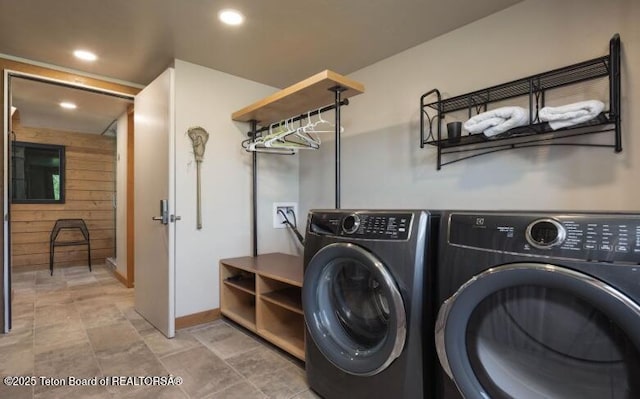 laundry room with washing machine and clothes dryer, wood walls, recessed lighting, baseboards, and stone finish floors