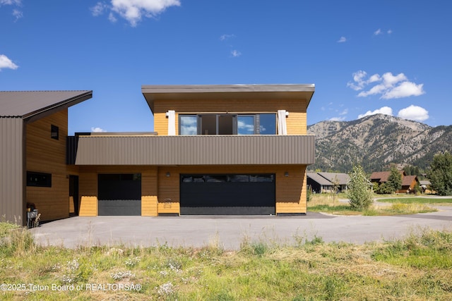 modern home with a mountain view, concrete driveway, and a garage