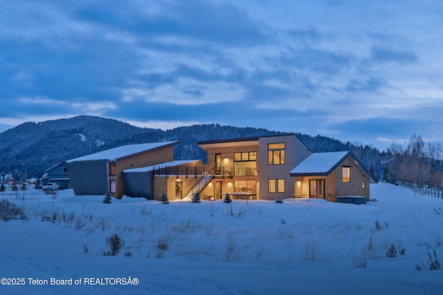 snow covered property featuring a mountain view and stairs