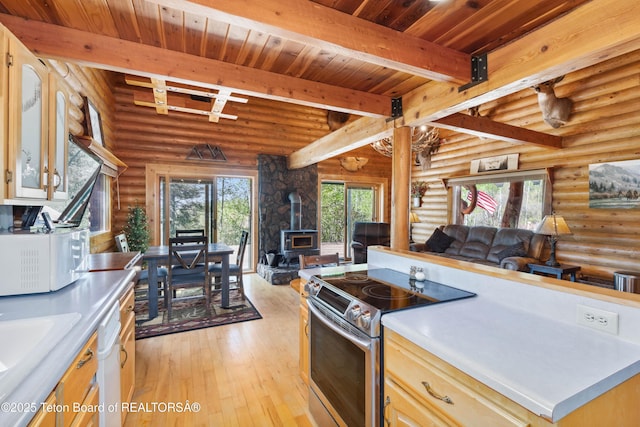 185 River Bench Rd, Thayne, WY 83127 - kitchen featuring white appliances, a wood stove, open floor plan, beamed ceiling, and rustic walls