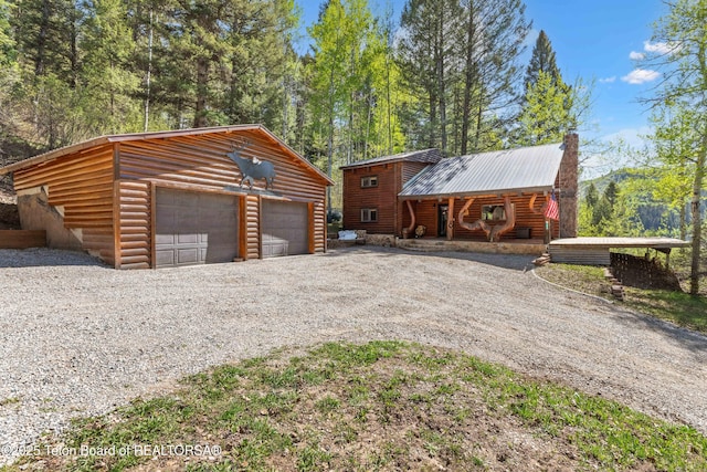 185 River Bench Rd, Thayne, WY 83127 - view of front facade featuring a garage, an outbuilding, metal roof, a chimney, and faux log siding