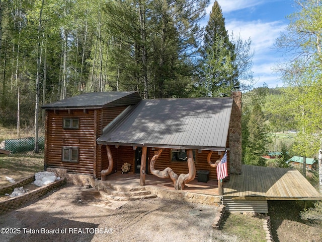 185 River Bench Rd, Thayne, WY 83127 - view of front of home with metal roof, a chimney, a view of trees, covered porch, and log siding