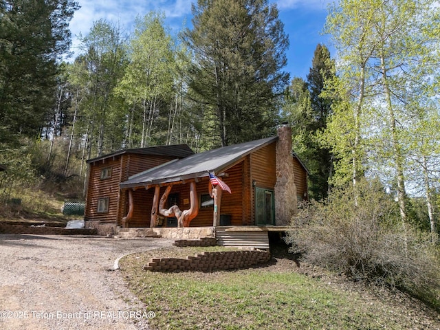 185 River Bench Rd, Thayne, WY 83127 - view of front of property featuring a porch, a chimney, dirt driveway, and metal roof