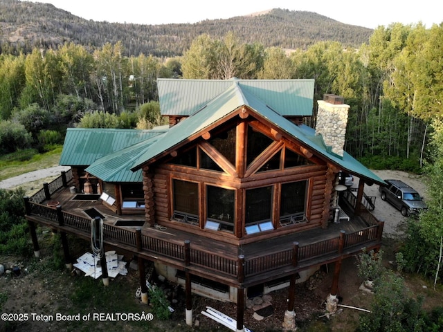 3 Forest Trl, Boulder, WY 82923 - back of property featuring a forest view, log exterior, a deck with mountain view, a chimney, and metal roof