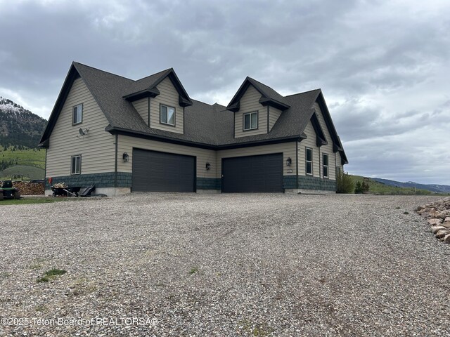 61 Astorian Ln, Smoot, WY 83126 - view of side of home with gravel driveway, a garage, and a mountain view