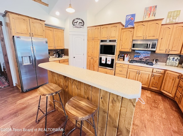 61 Astorian Ln, Smoot, WY 83126 - kitchen with stainless steel appliances, decorative backsplash, light wood-style floors, light countertops, and a kitchen island