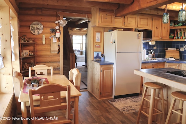 31 Cutoff Rd, Daniel, WY 83115 - kitchen featuring freestanding refrigerator, tile counters, rustic walls, dark wood-type flooring, and backsplash