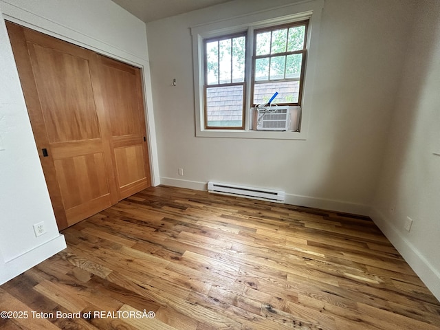 9064 Village Way, Victor, ID 83455 - unfurnished bedroom with a baseboard radiator, wood finished floors, cooling unit, a closet, and baseboards